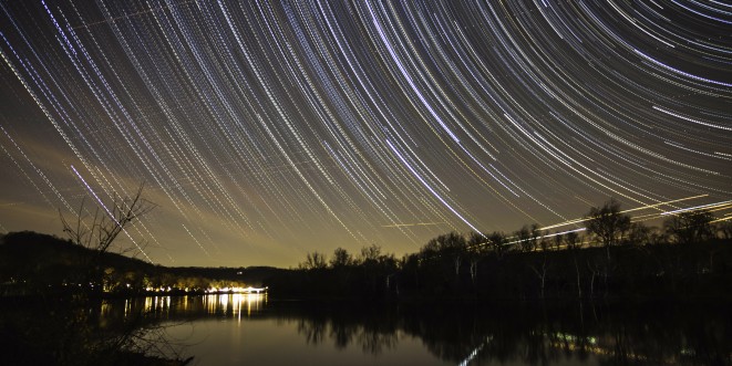 Nighttime view of a river, with glowing lines in the night sky.