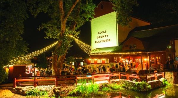 Bucks County Playhouse from the outside with a crowd of people, lit up with green lights.