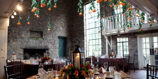 A stone interior building, decorated with hanging flowers, candles, and table decorations.