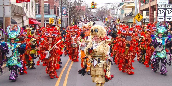 A formation of people in costume, dancing in a parade.