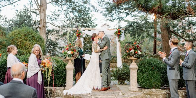 Bride and groom kissing at the altar, with bridal party on either side.