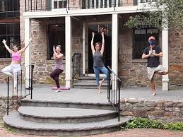 People dressed in fitness clothes doing yoga poses on a stone porch.