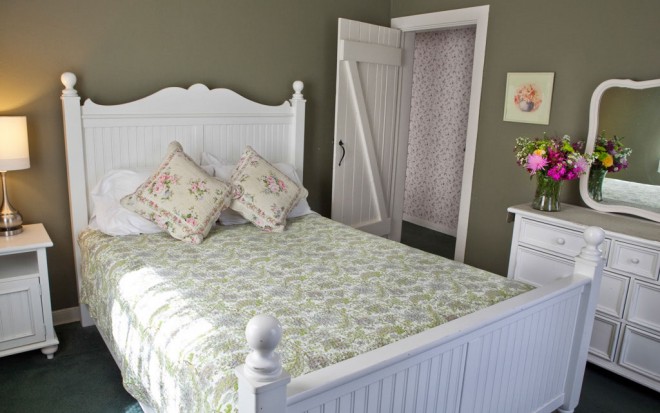 Photo of Room 12: A deluxe room with a white wooden bed, white wooden dresser and night stand