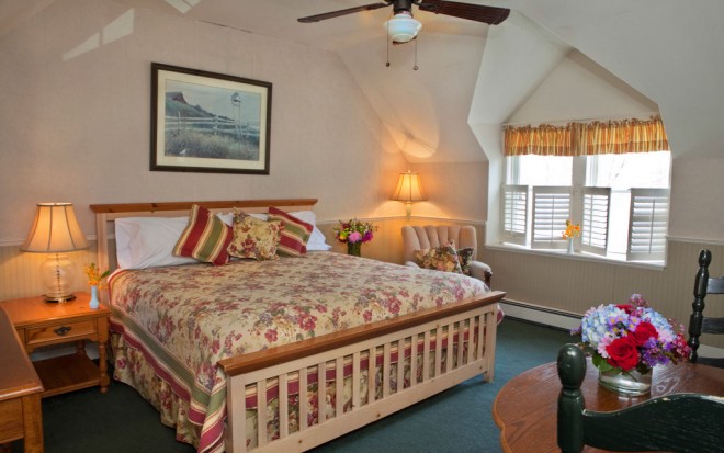 Photo of Room 16: A deluxe room with a large wood bed, small table and chairs, an arm chair and ceiling fan