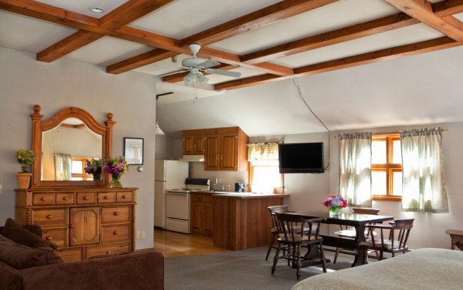 Photo of Room 18: A large open-concept suite with a half-kitchen, table and chairs, a dresser, and a TV on the wall.