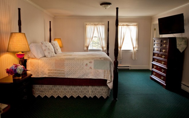 Photo of Room 2: A junior suite with a mahogany sleigh bed that faces a dresser and TV