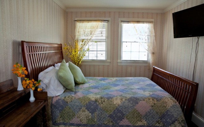 Photo of Room 4: A standard room with two windows, a dark wood bed, and a TV hanging on the wall