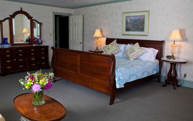 Photo of Room 7: A junior suite with a traditional dark wood bed, side tables, and dresser