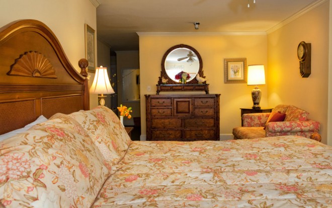 Photo of Room 8: A junior suite room with warm oak wood bed and floral blanket, an oak dresser, and a small couch