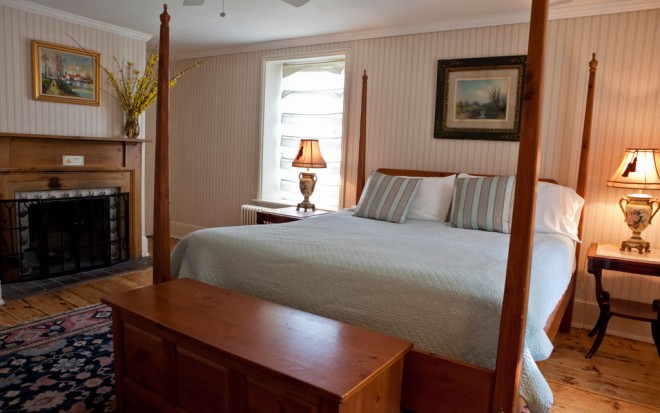 Photo of Room 9: A traditional master suite with a wood canopy bed, fireplace, and wood floors